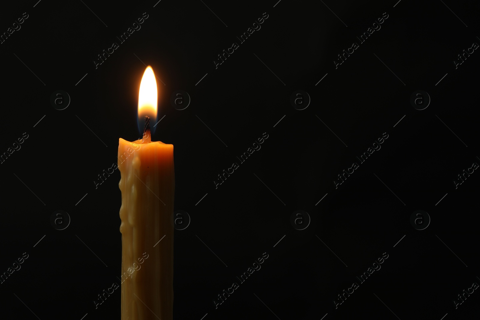 Photo of One burning church candle on black background, space for text