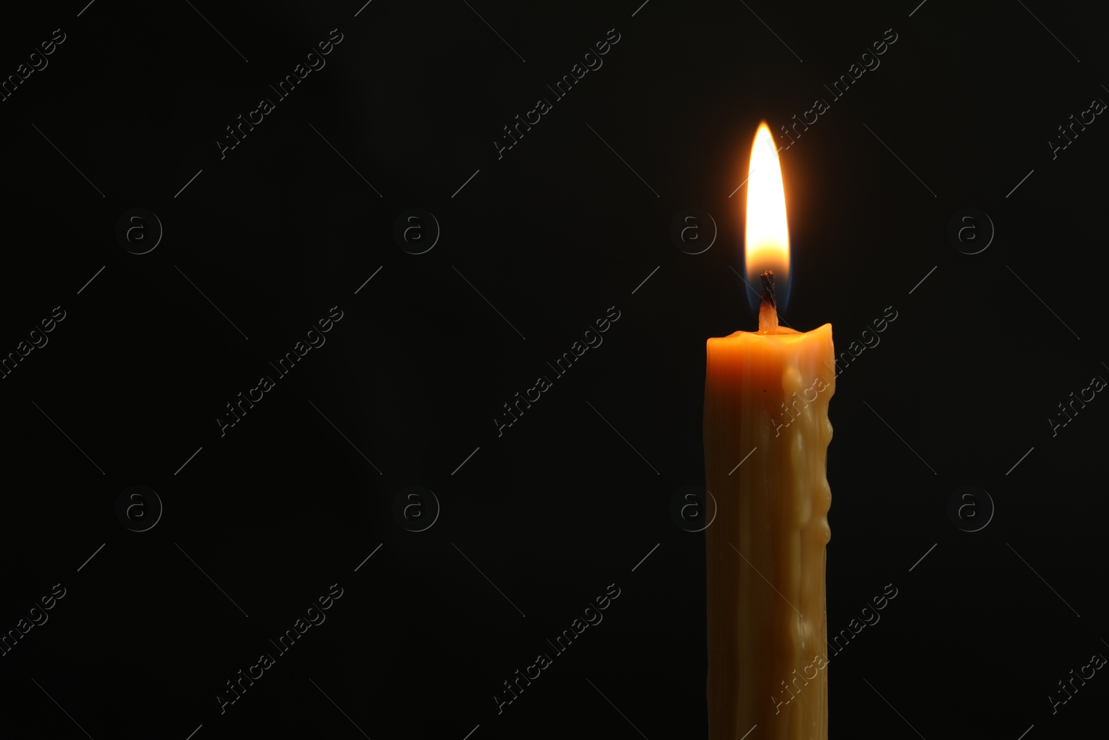 Photo of One burning church candle on black background, space for text