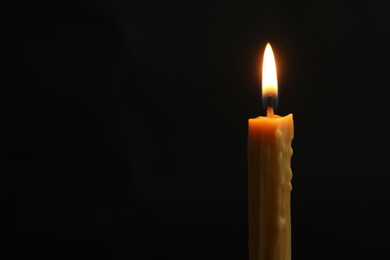 Photo of One burning church candle on black background, space for text