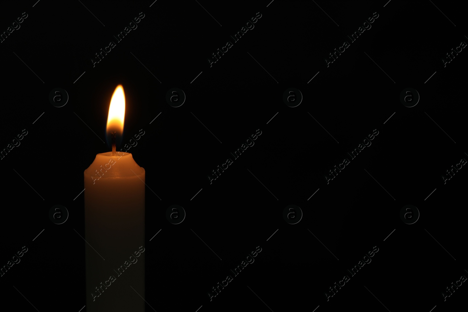 Photo of One burning church candle on black background, space for text