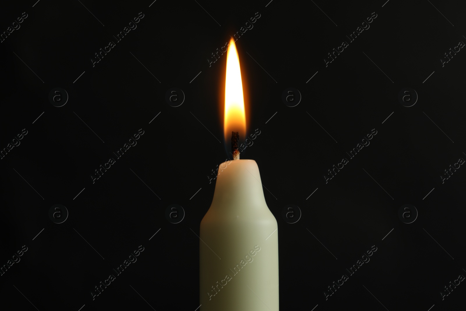 Photo of One burning church candle on black background, closeup