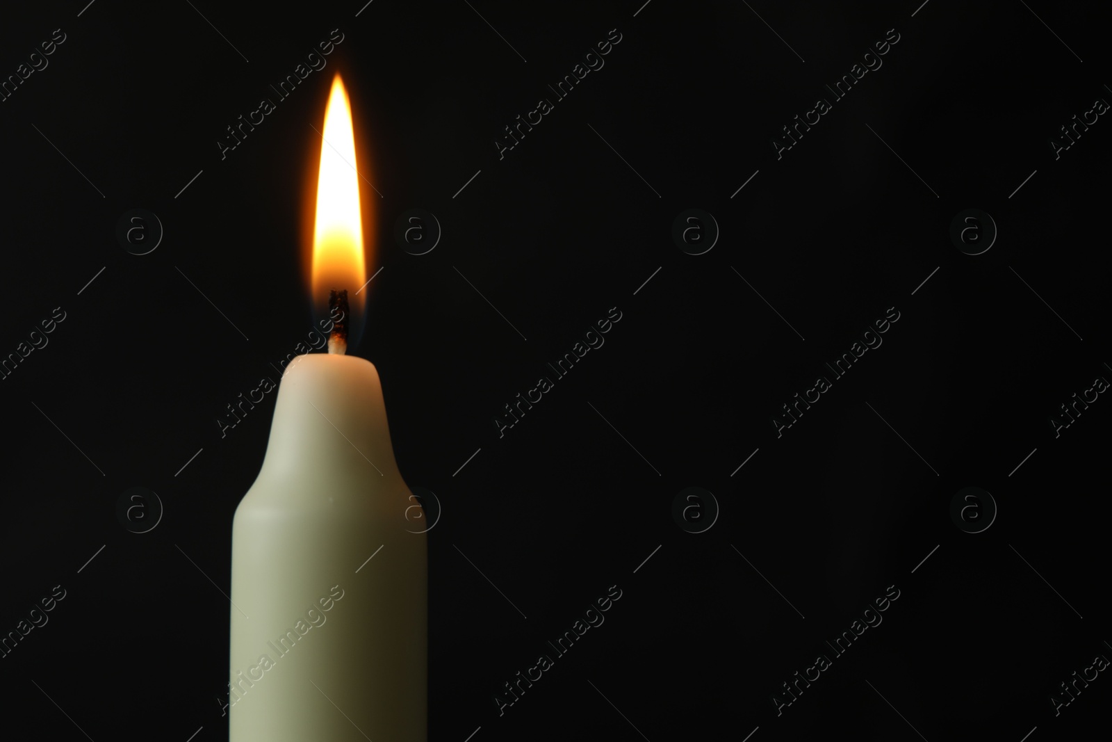 Photo of One burning church candle on black background, closeup. Space for text