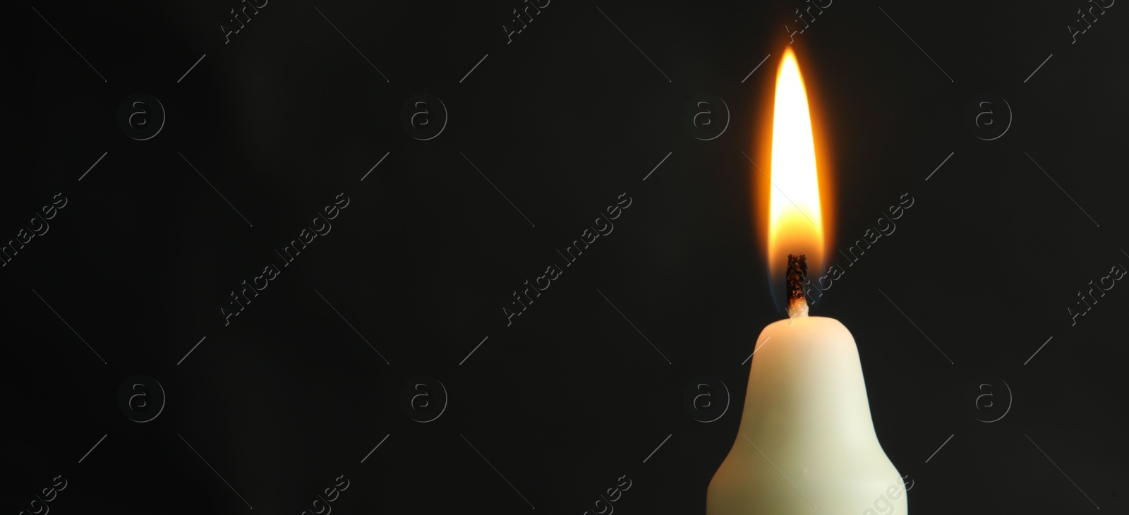 Photo of One burning church candle on black background, closeup. Space for text