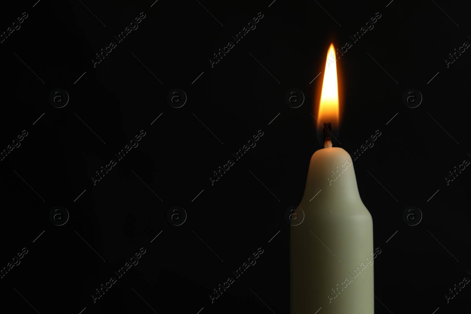 Photo of One burning church candle on black background, closeup. Space for text