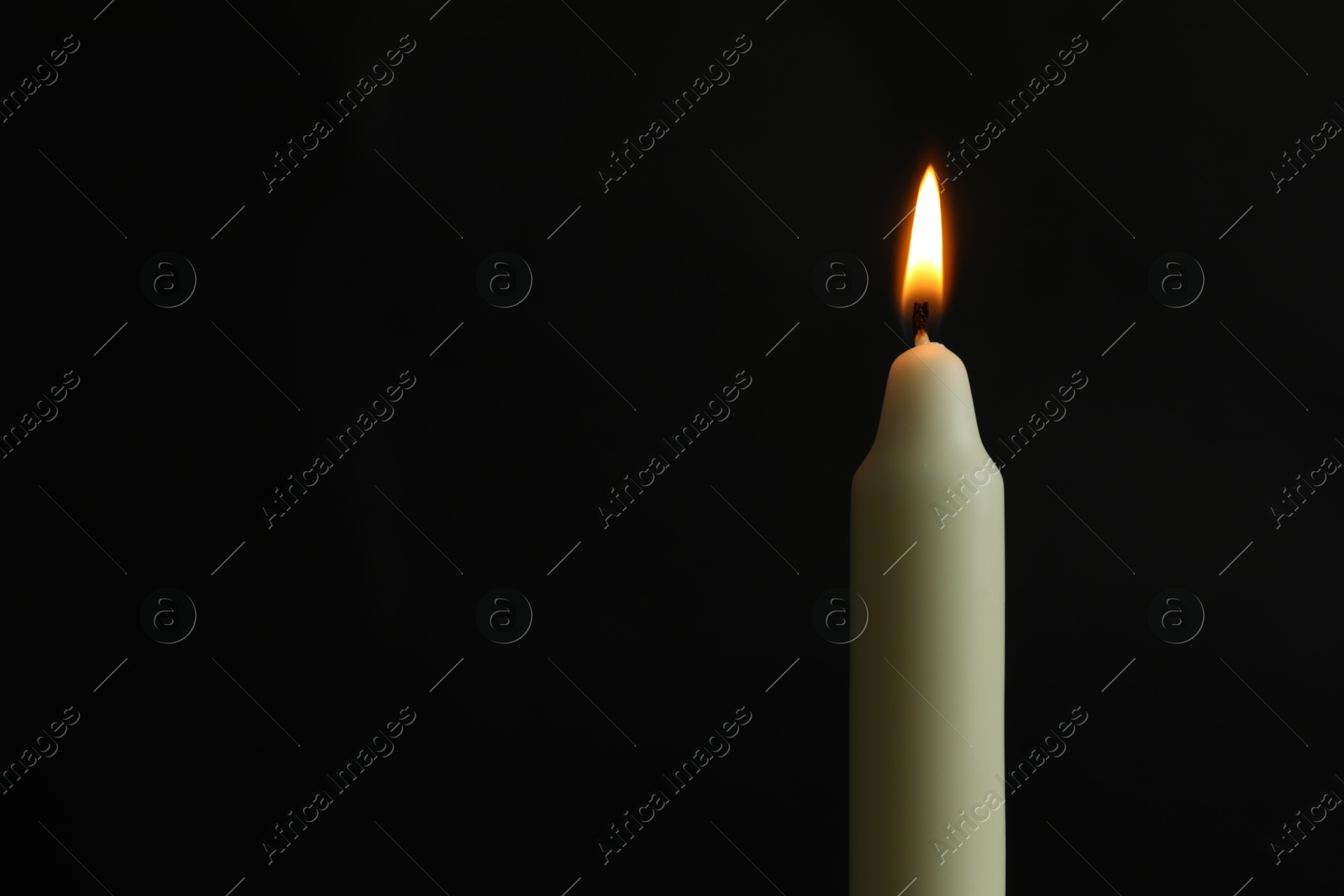 Photo of One burning church candle on black background, space for text