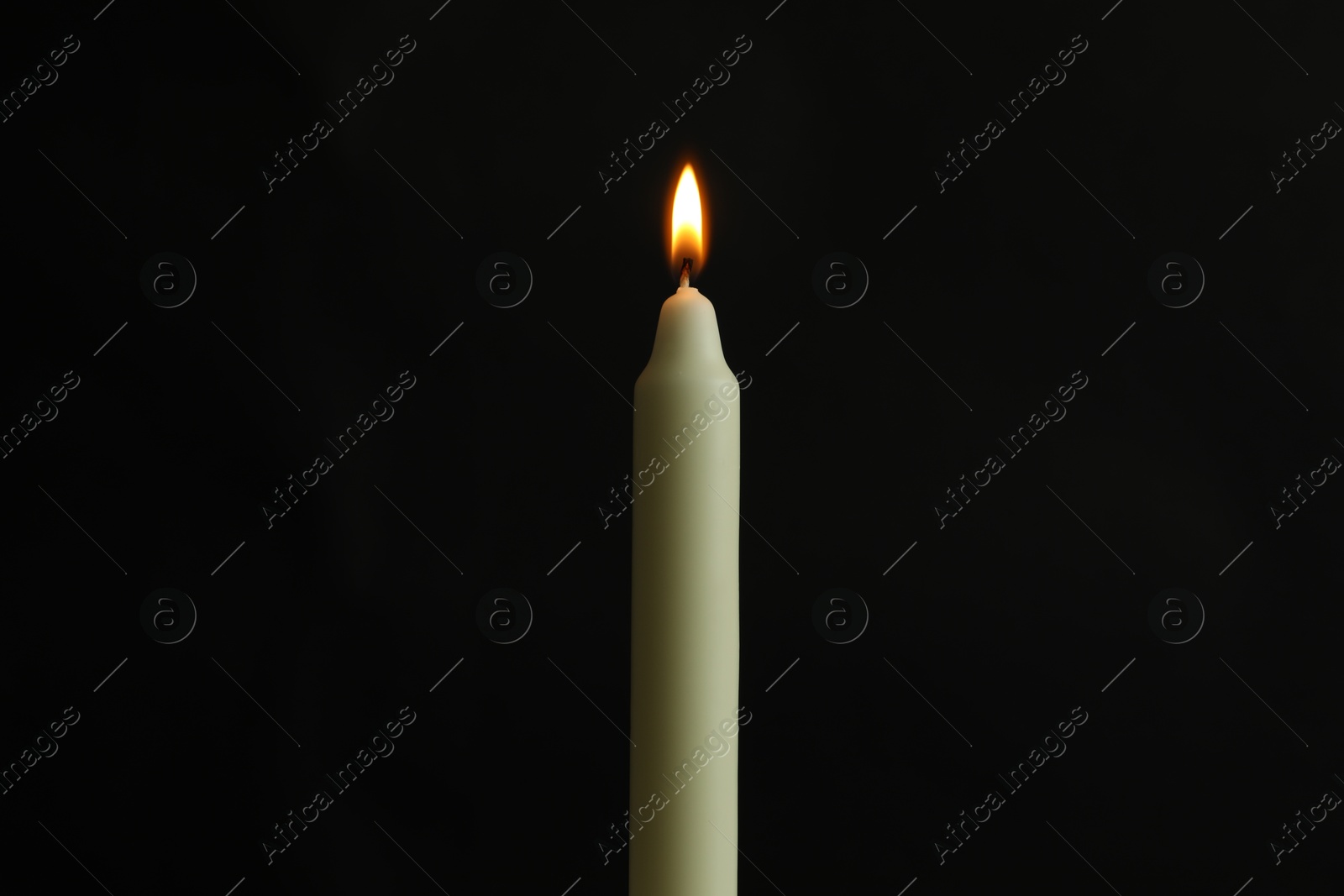 Photo of One burning church candle on black background