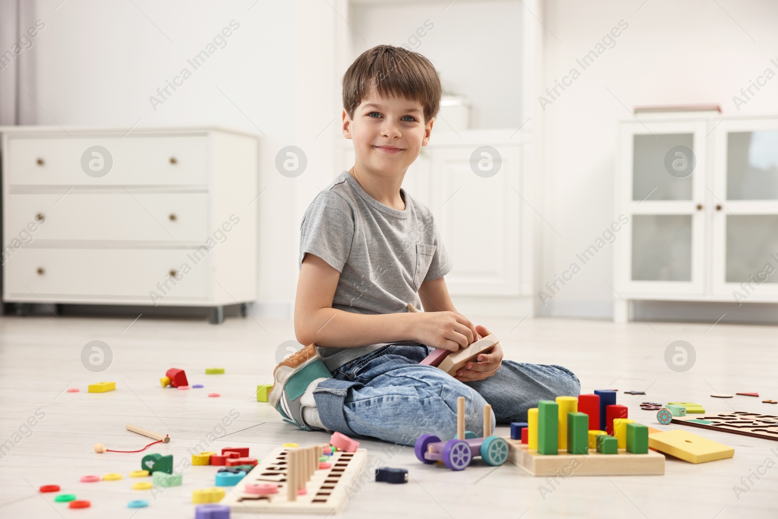Photo of Cute little boy playing with toy pyramid on floor indoors