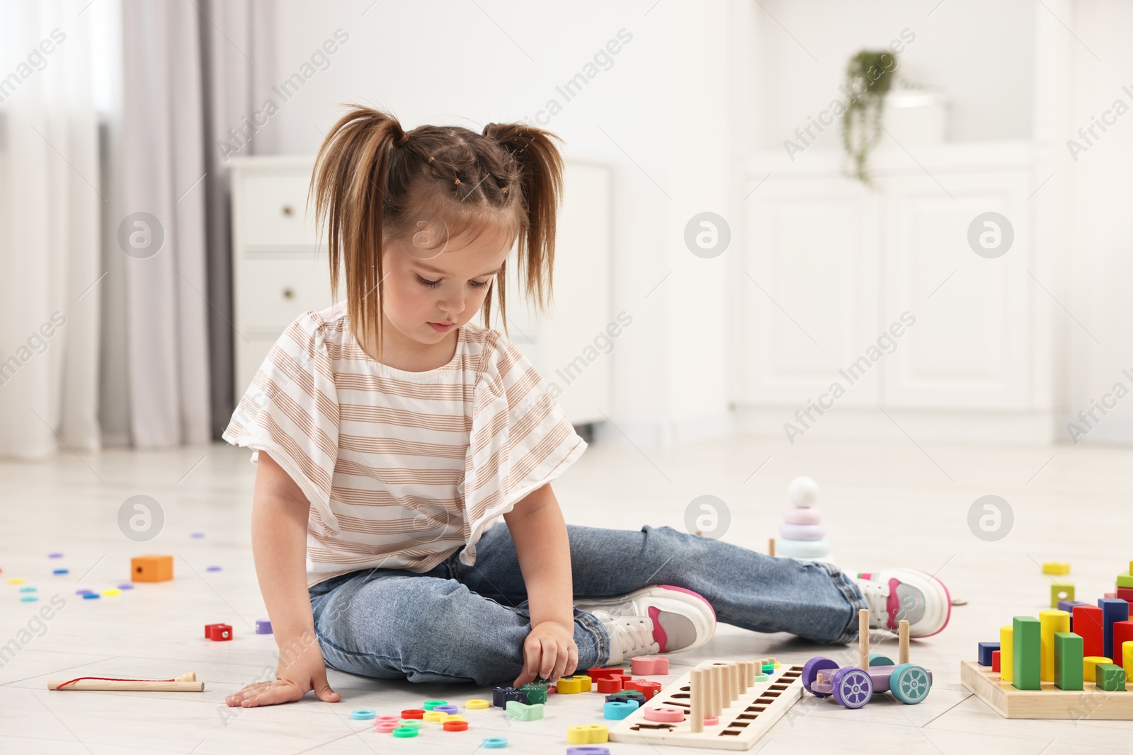 Photo of Cute little girl playing with math game Fishing for Numbers on floor indoors