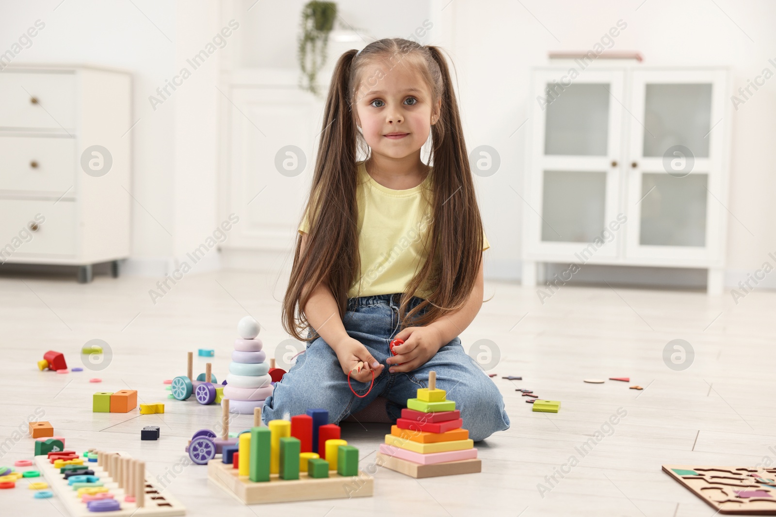 Photo of Cute little girl playing on floor indoors