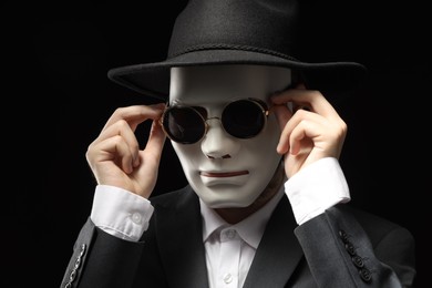 Photo of Theatrical performance. Man with plastic mask and sunglasses on black background
