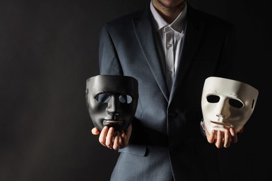 Theatrical performance. Man holding plastic masks on black background, closeup. Space for text