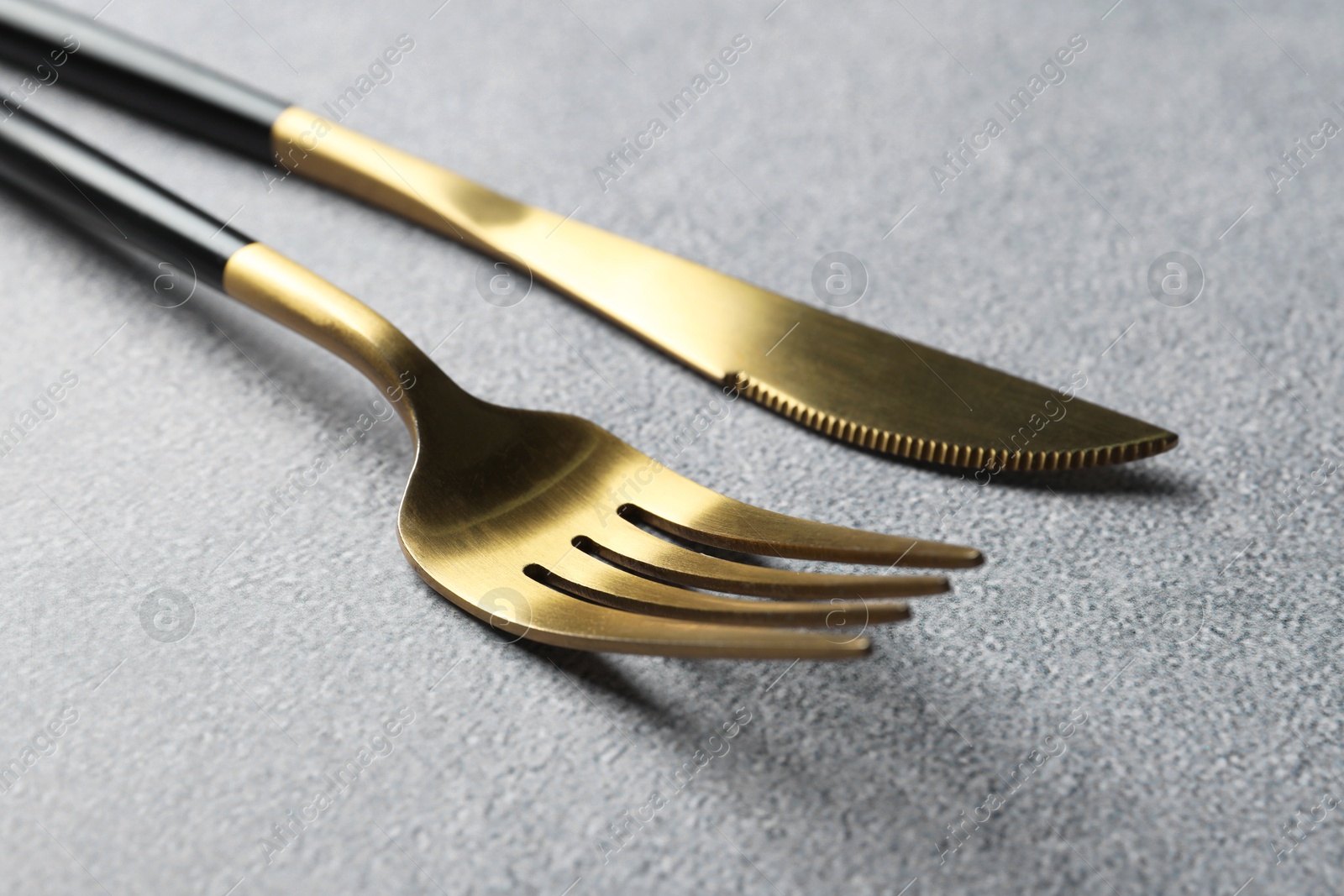 Photo of Stylish golden cutlery on grey table, closeup