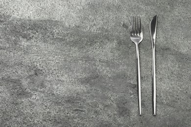 Stylish silver cutlery on grey table, top view. Space for text