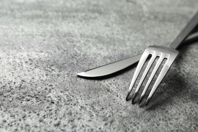 Photo of Stylish silver cutlery on grey table, closeup. Space for text