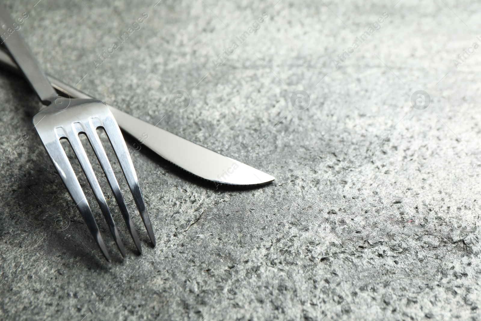 Photo of Stylish silver cutlery on grey table, closeup. Space for text