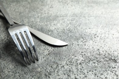 Photo of Stylish silver cutlery on grey table, closeup. Space for text