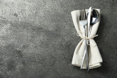 Photo of Stylish silver cutlery and napkin on grey table, top view. Space for text