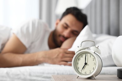 Photo of Man sleeping on bed at morning, focus on alarm clock