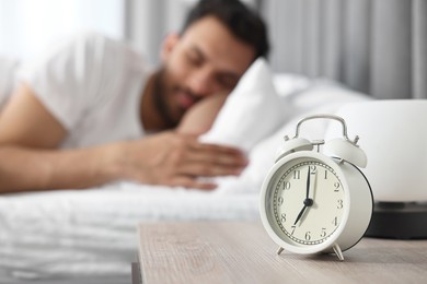 Photo of Man sleeping on bed at morning, focus on alarm clock