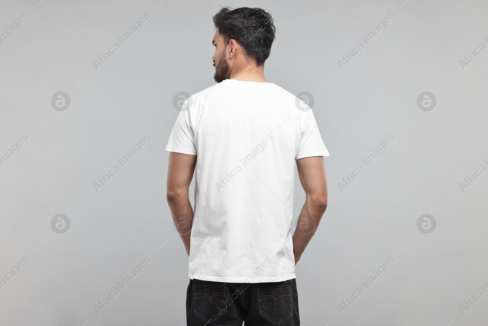 Photo of Man in white t-shirt on grey background, back view