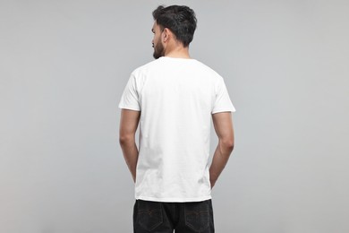 Man in white t-shirt on grey background, back view