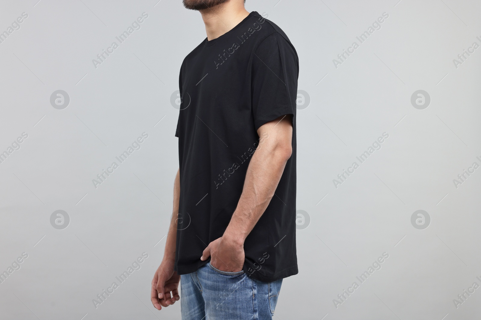 Photo of Man in black t-shirt on grey background, closeup