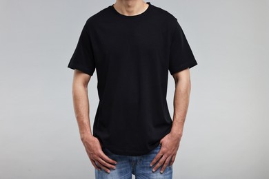 Man in black t-shirt on grey background, closeup