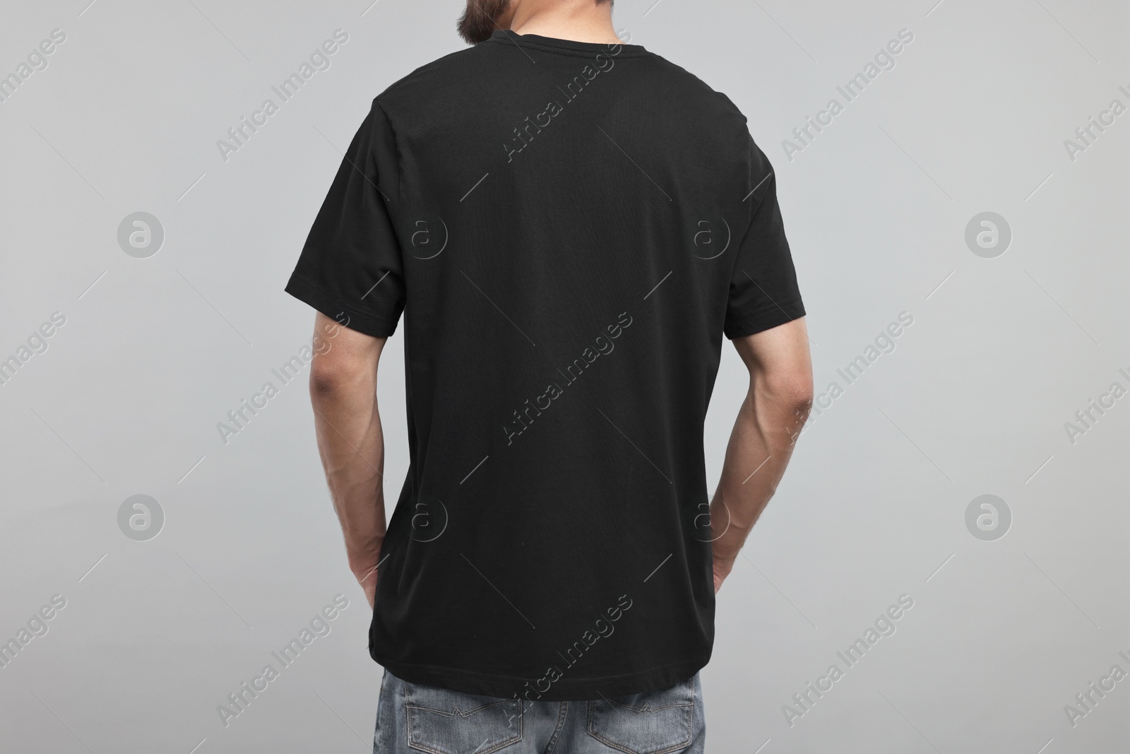 Photo of Man in black t-shirt on grey background, back view