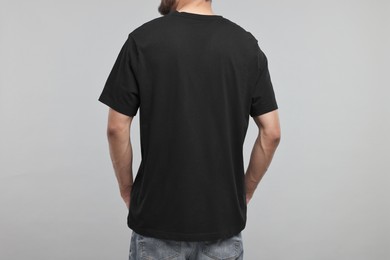 Man in black t-shirt on grey background, back view