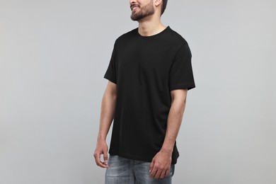 Smiling man in black t-shirt on grey background, closeup