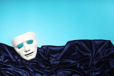 Theater arts. White mask and fabric on light blue background, top view. Space for text