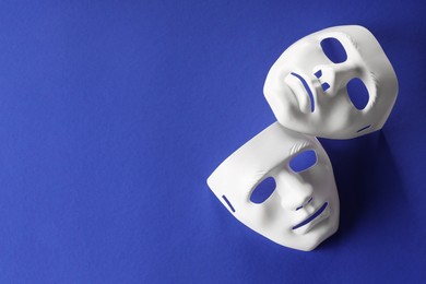 Photo of Theater arts. White masks on blue background, top view. Space for text