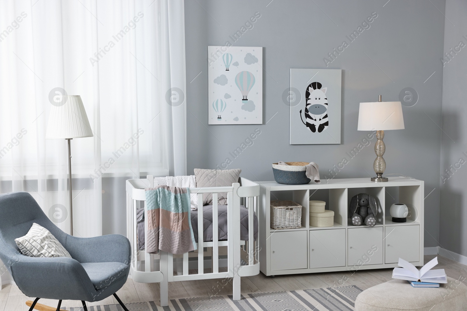 Photo of Newborn baby room interior with stylish furniture, comfortable crib and pictures of on wall