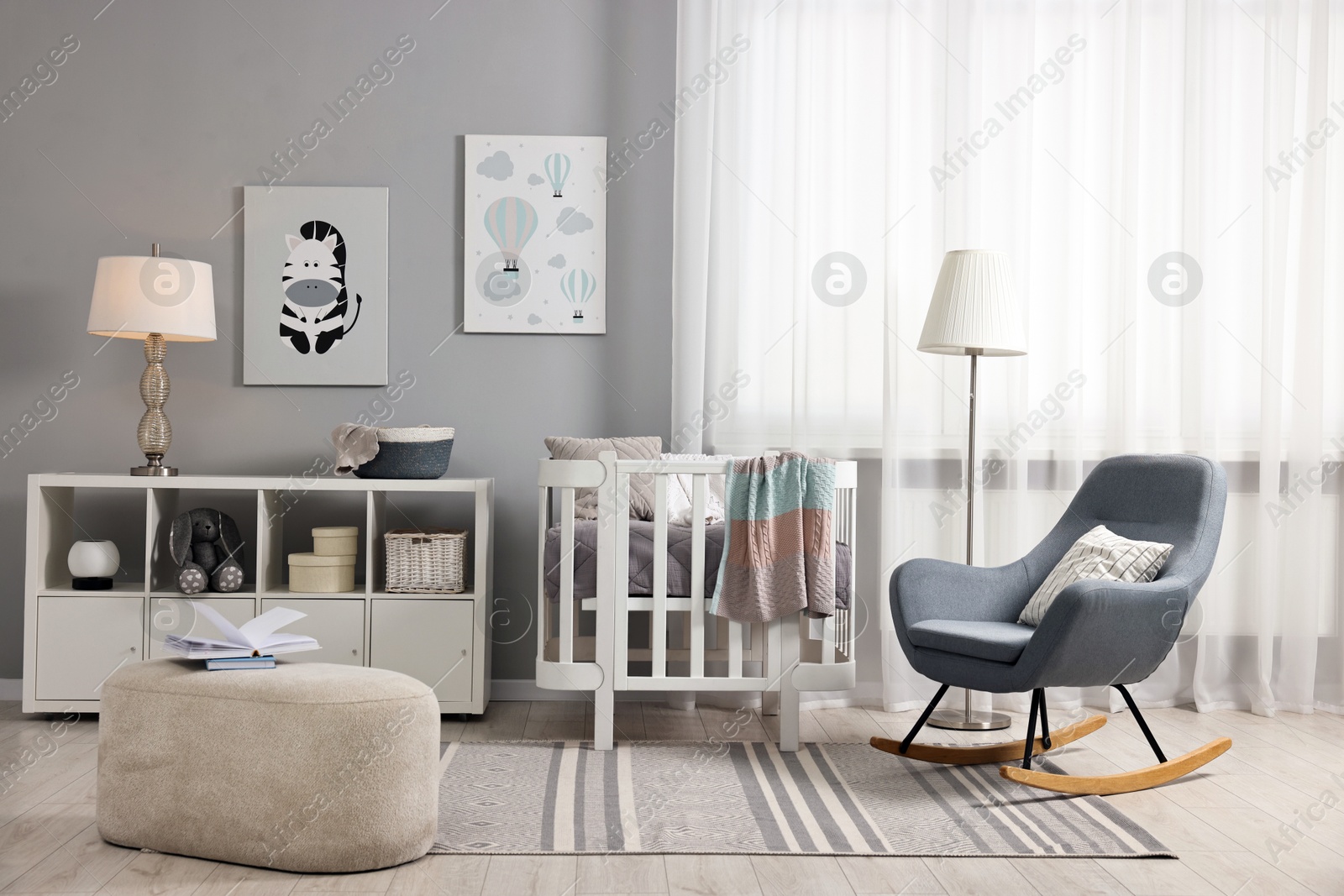 Photo of Newborn baby room interior with stylish furniture, comfortable crib and pictures of on wall
