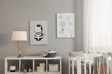 Newborn baby room interior with stylish furniture, comfortable crib and pictures of on wall