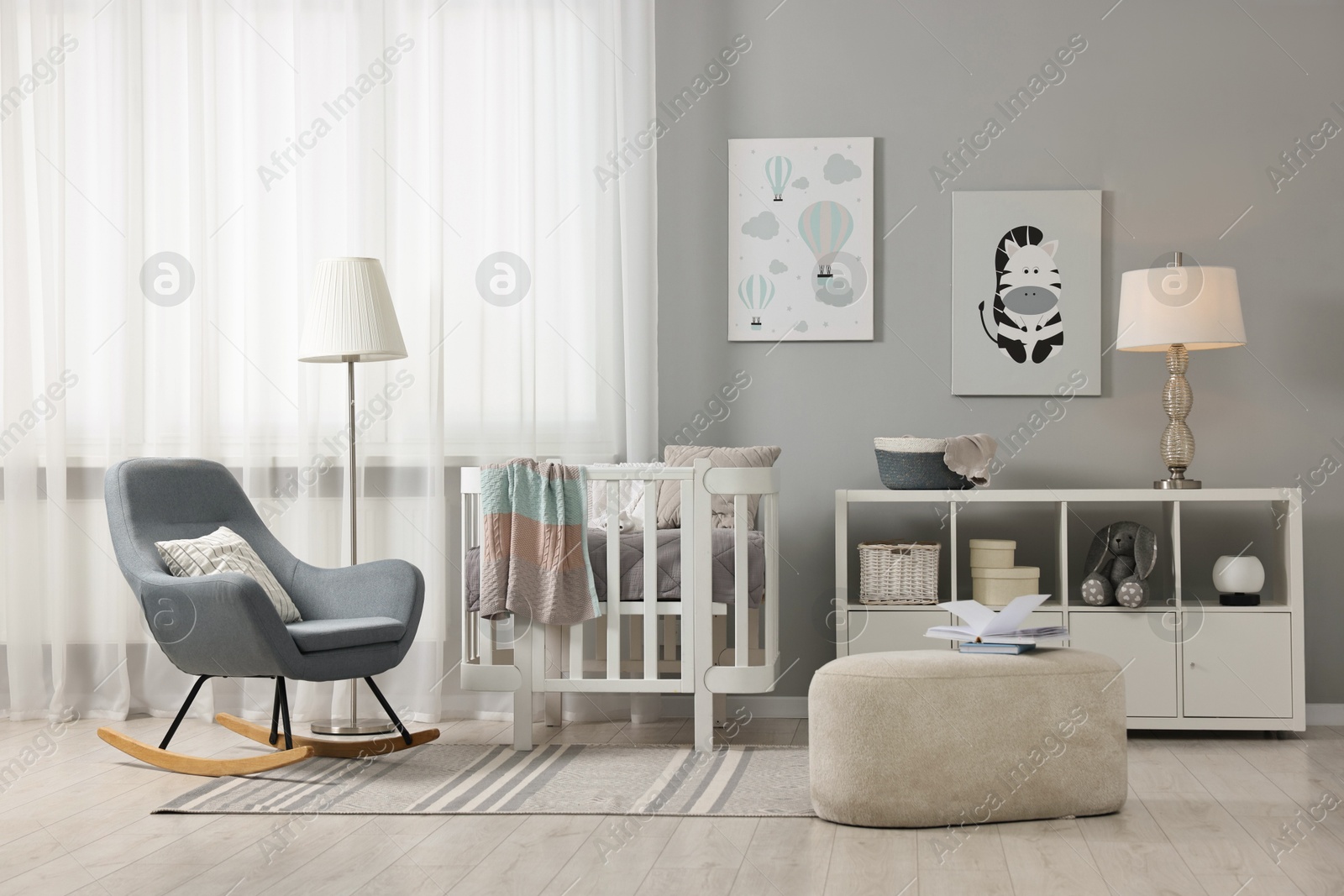 Photo of Newborn baby room interior with stylish furniture, comfortable crib and pictures of on wall