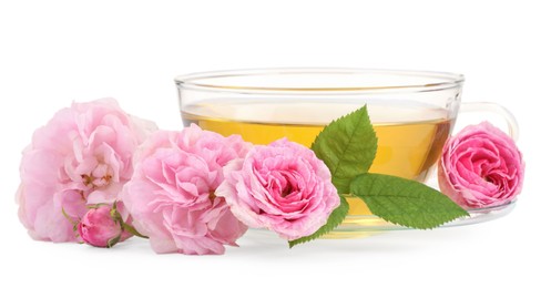 Photo of Aromatic herbal tea in glass cup, flowers and green leaves isolated on white