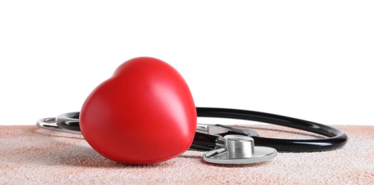 Stethoscope and red heart on color textured table against white background