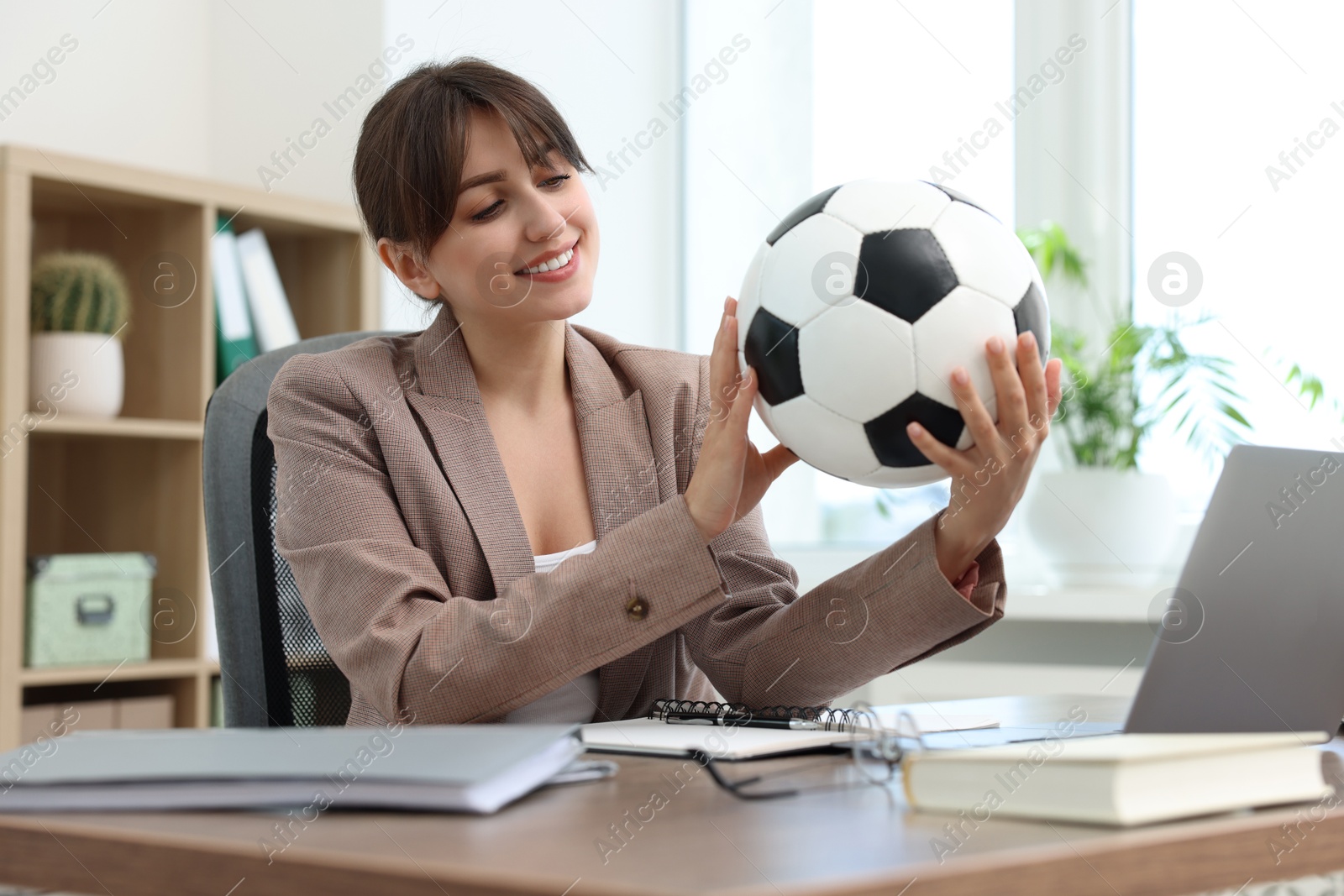 Photo of Smiling employee with soccer ball at table in office