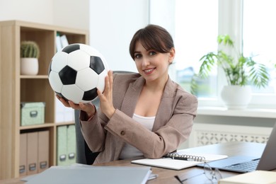 Photo of Smiling employee with soccer ball at table in office