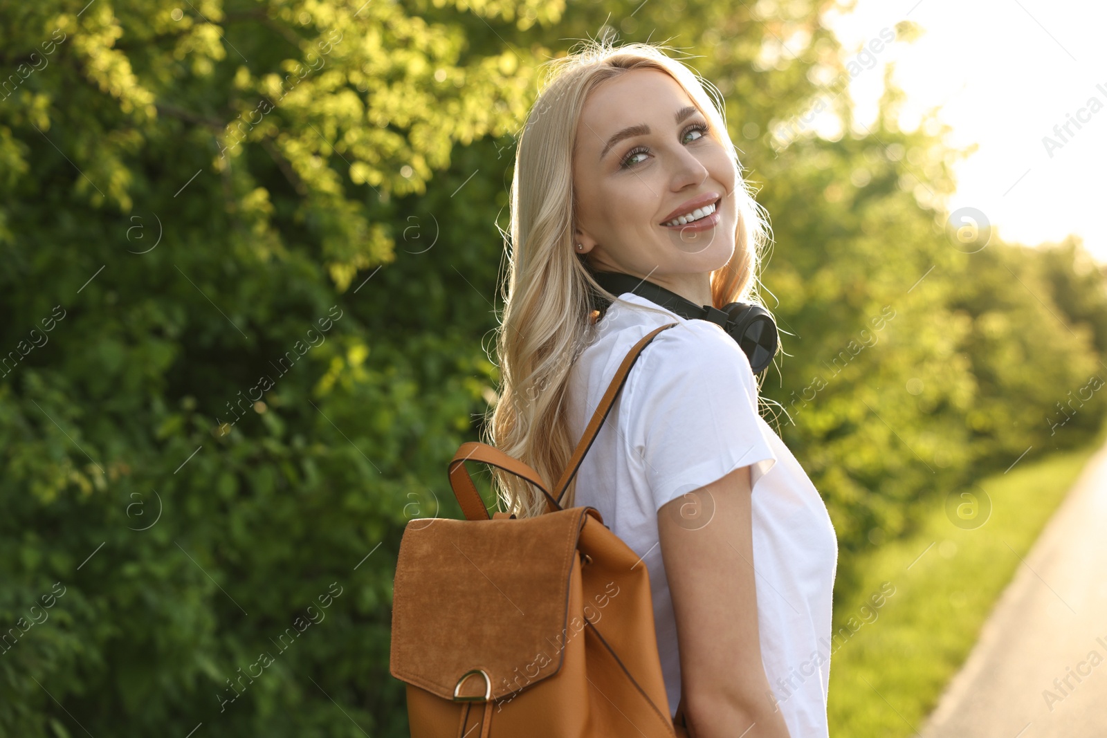 Photo of Happy young woman with headphones in park on spring day