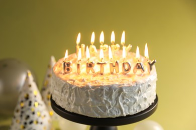 Photo of Tasty birthday cake with burning candles on green background, closeup