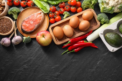 Photo of Many different healthy food on dark textured table, flat lay. Space for text