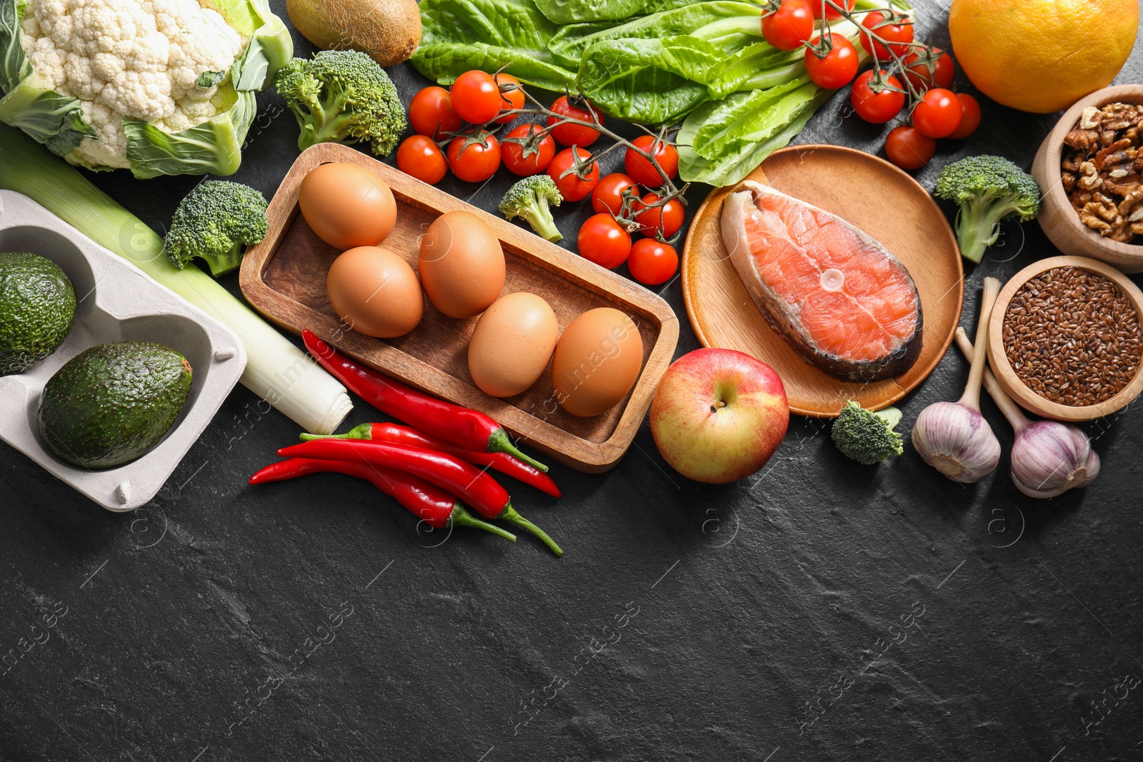 Photo of Many different healthy food on dark textured table, flat lay. Space for text