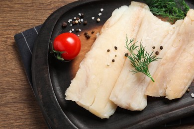 Photo of Raw cod fish, dill, tomatoes and spices on wooden table, top view