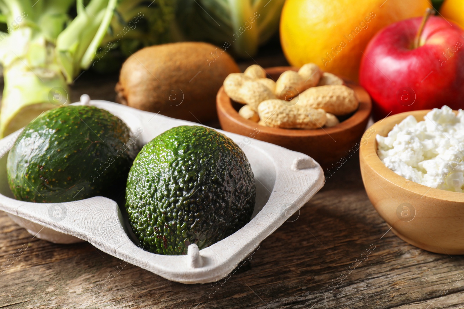 Photo of Healthy meal. Different vegetables and cheese on wooden table, closeup