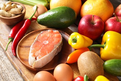 Photo of Healthy meal. Different vegetables and raw salmon on wooden table, closeup