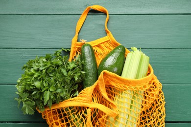String bag with different vegetables on green wooden table, top view