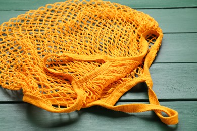 Orange string bag on green wooden table, closeup