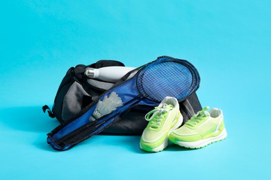 Badminton set, bag, sneakers and bottle on light blue background